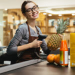 happy-female-cashier-scanning-grocery-items-e1667853709401
